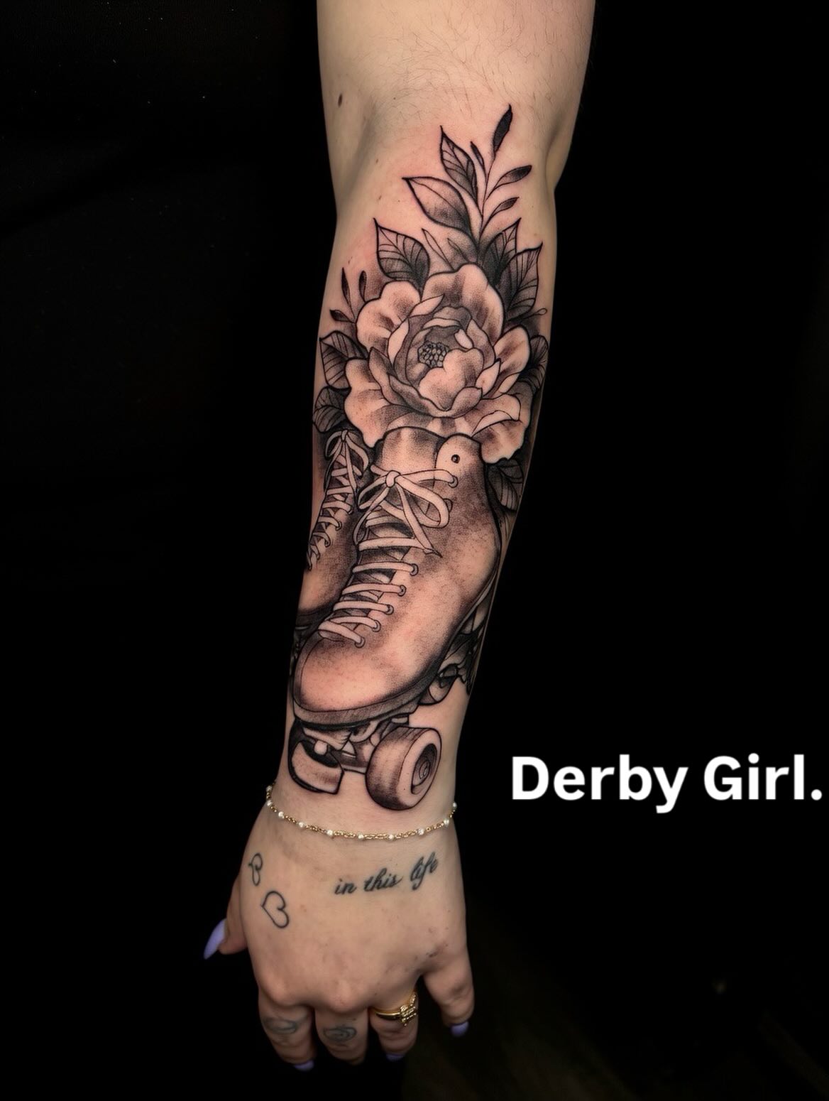 Roller derby and floral forearm tattoo by Lucas Macauley