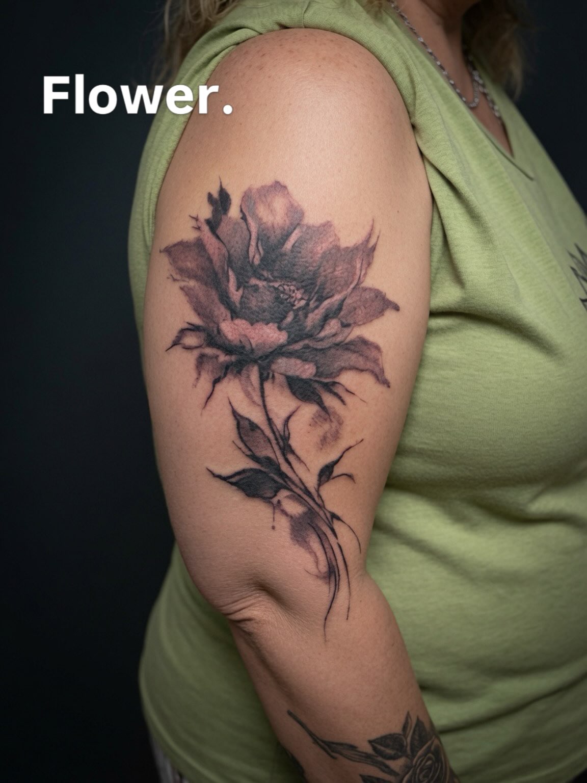 Soft black-and-grey flower upper-arm tattoo by Lucas Macauley